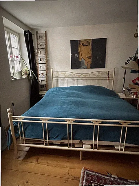 El fenbeinfarbenes Vintage-Metallbett mit zwei Beistelltischen.